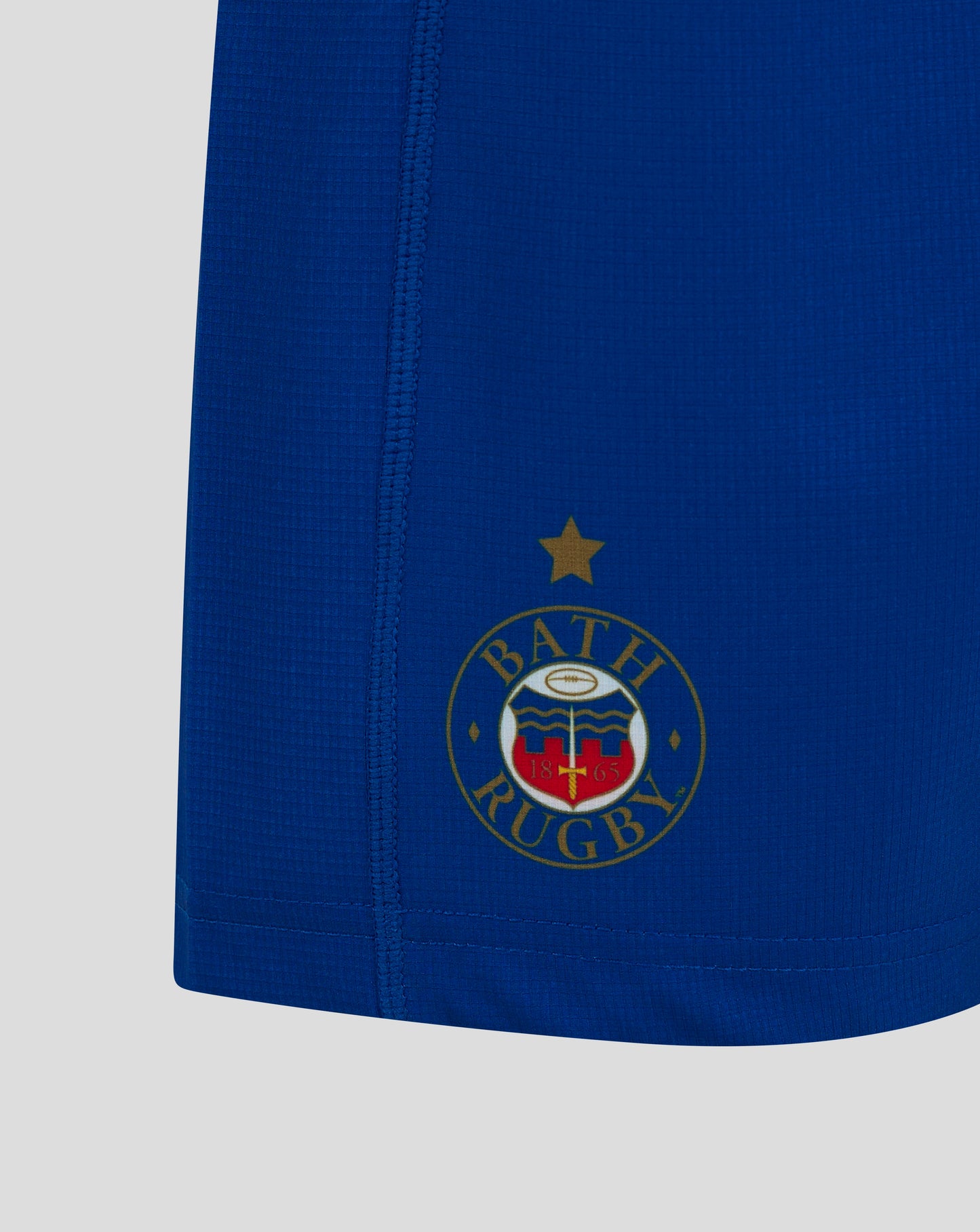 Close up of blue Bath Rugby Junior Away Shorts showing the Bath Rugby crest on the right thigh.