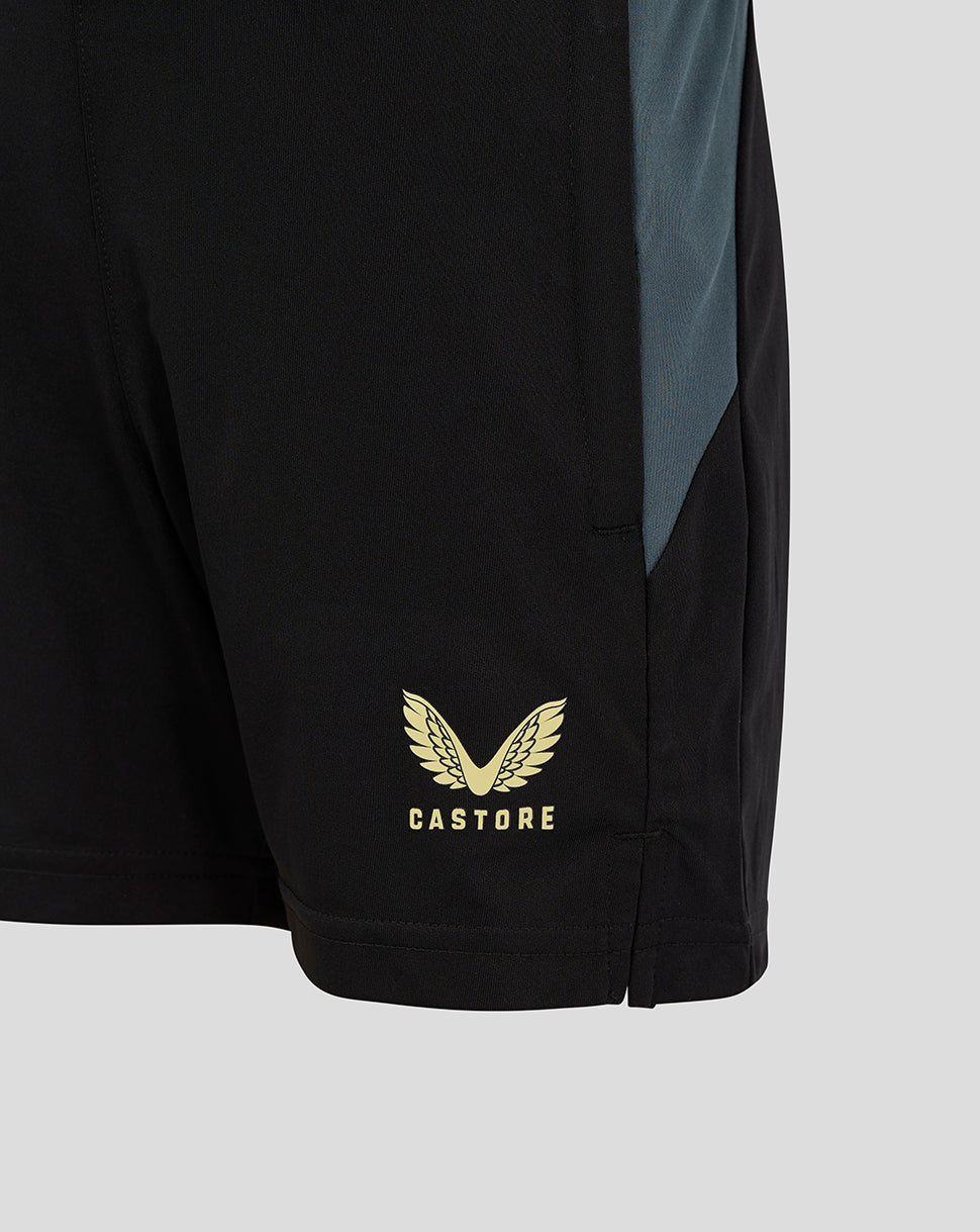 Gold Castore wing logo at the hem of black junior training shorts with teal side panel