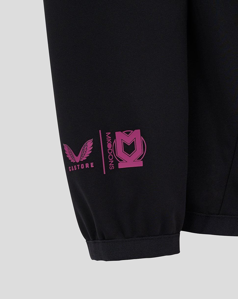 Detail of the black Mk Dons travel pants leg with pink logo and Castore emblem at the cuff