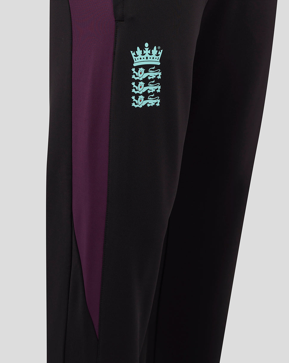 Close up of pant leg showing turquoise crest logo on black fabric with a purple panel.