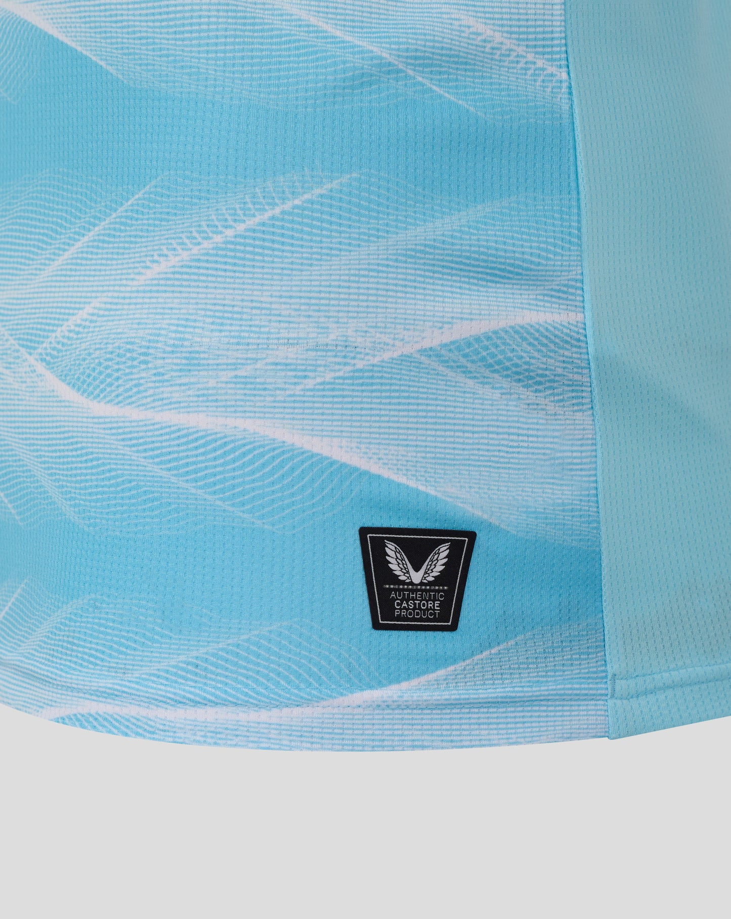 Close up of Burnley FC 25/26 away shirt fabric in light blue with a black authenticity patch featuring wings.