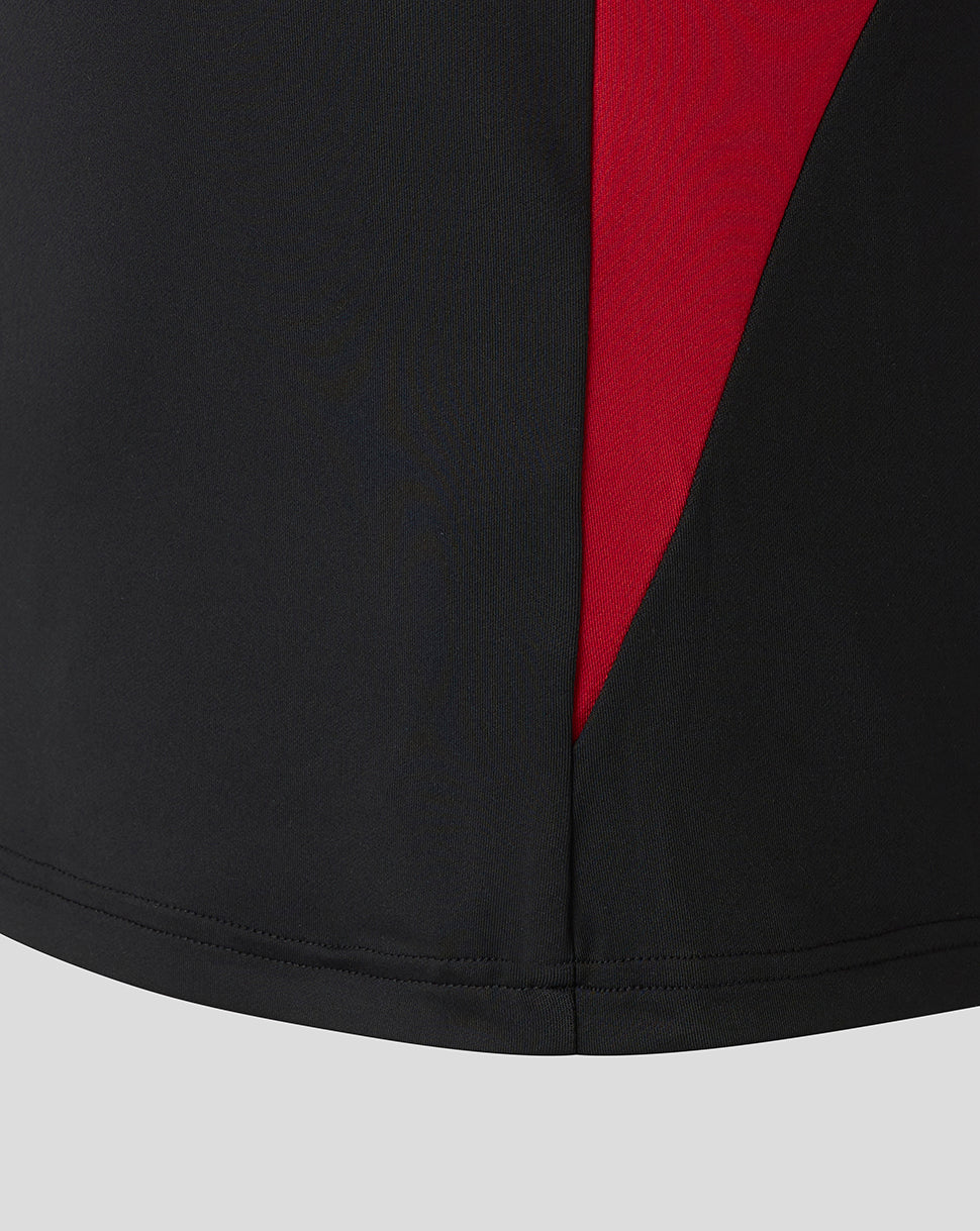 Close up of hem featuring a red diagonal panel on a black Saracens training top