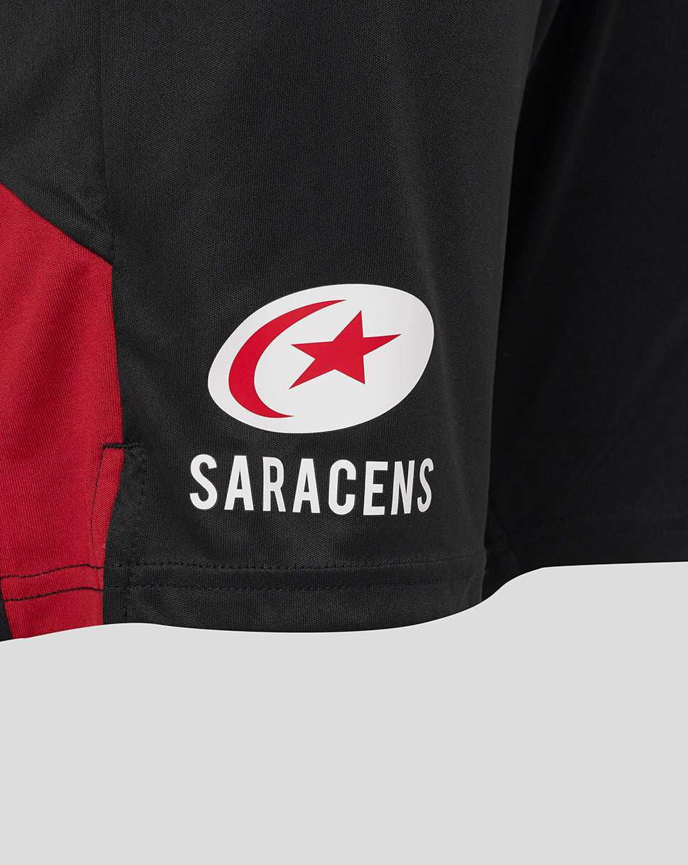 Close-up of black shorts showing the Saracens logo on the leg with a red panel detail