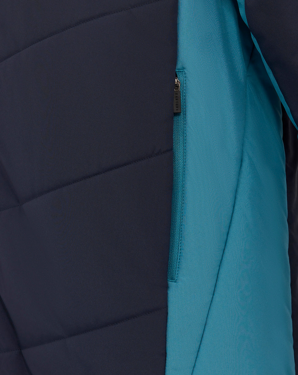 Close up of navy padded jacket showing teal side panel and teal zipper pocket along the side