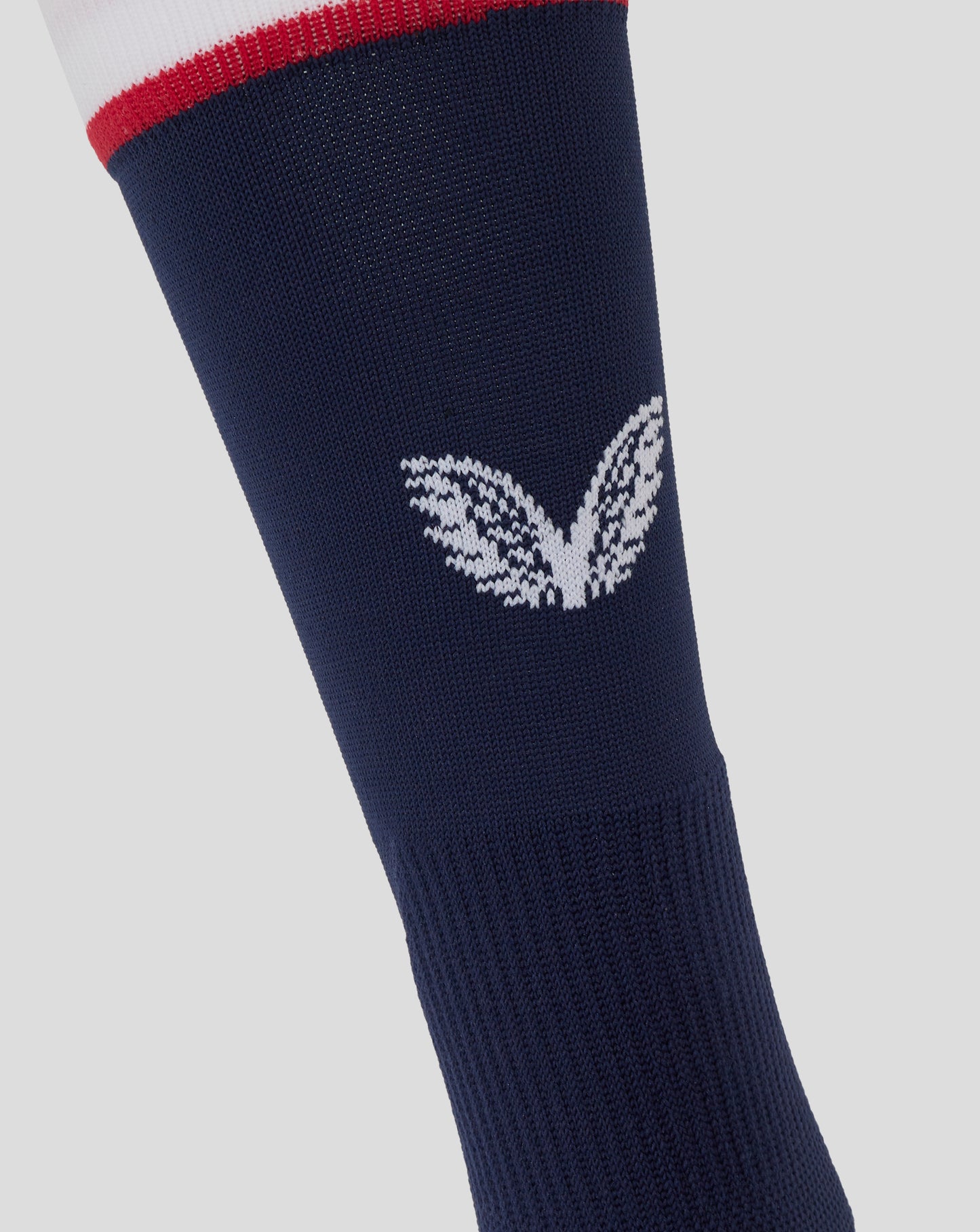 Close up of navy mid calf sock showing large white Castore wing logo and striped cuff