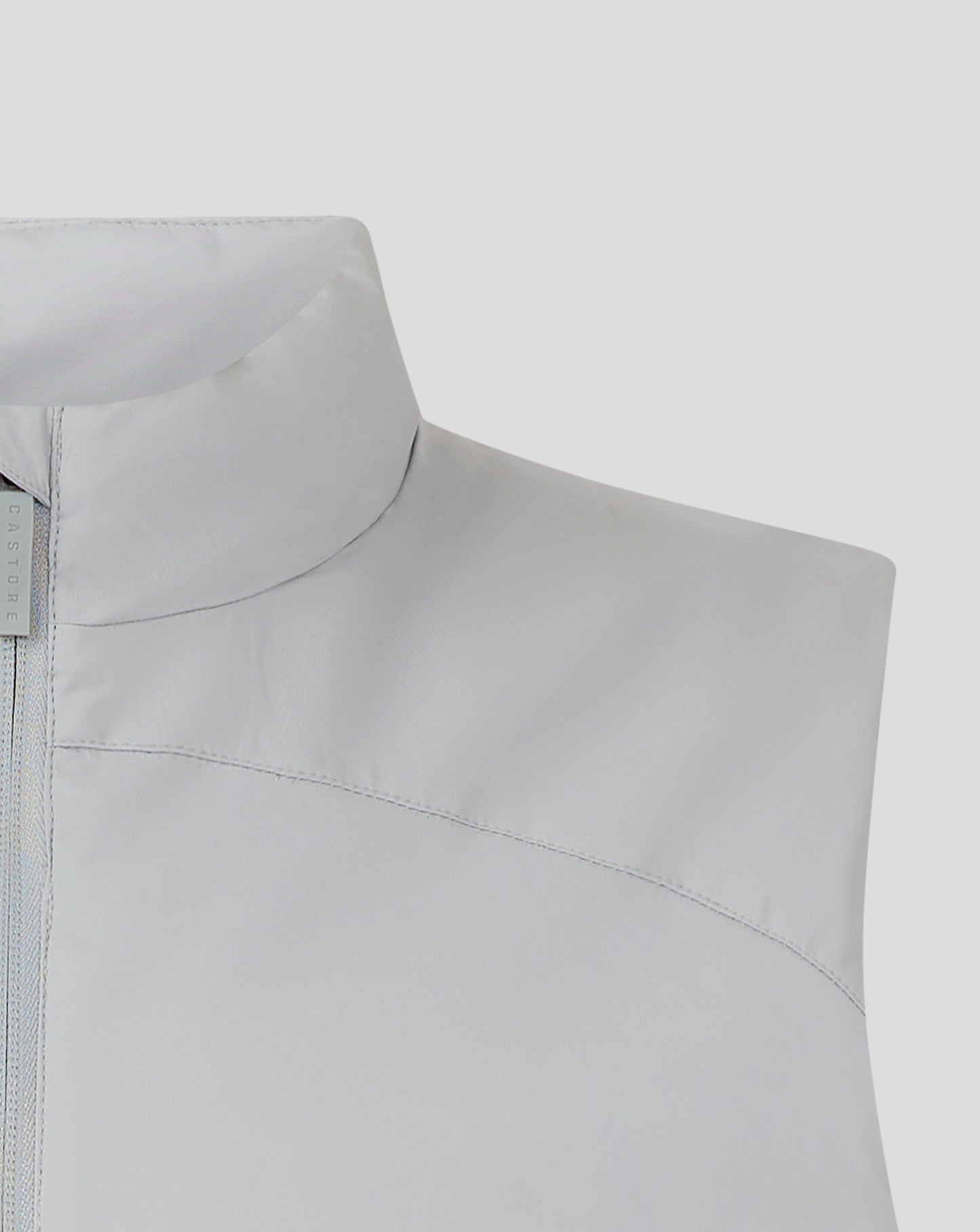 Shoulder and collar detail of light gray padded gilet with curved seams and Castore branding tag