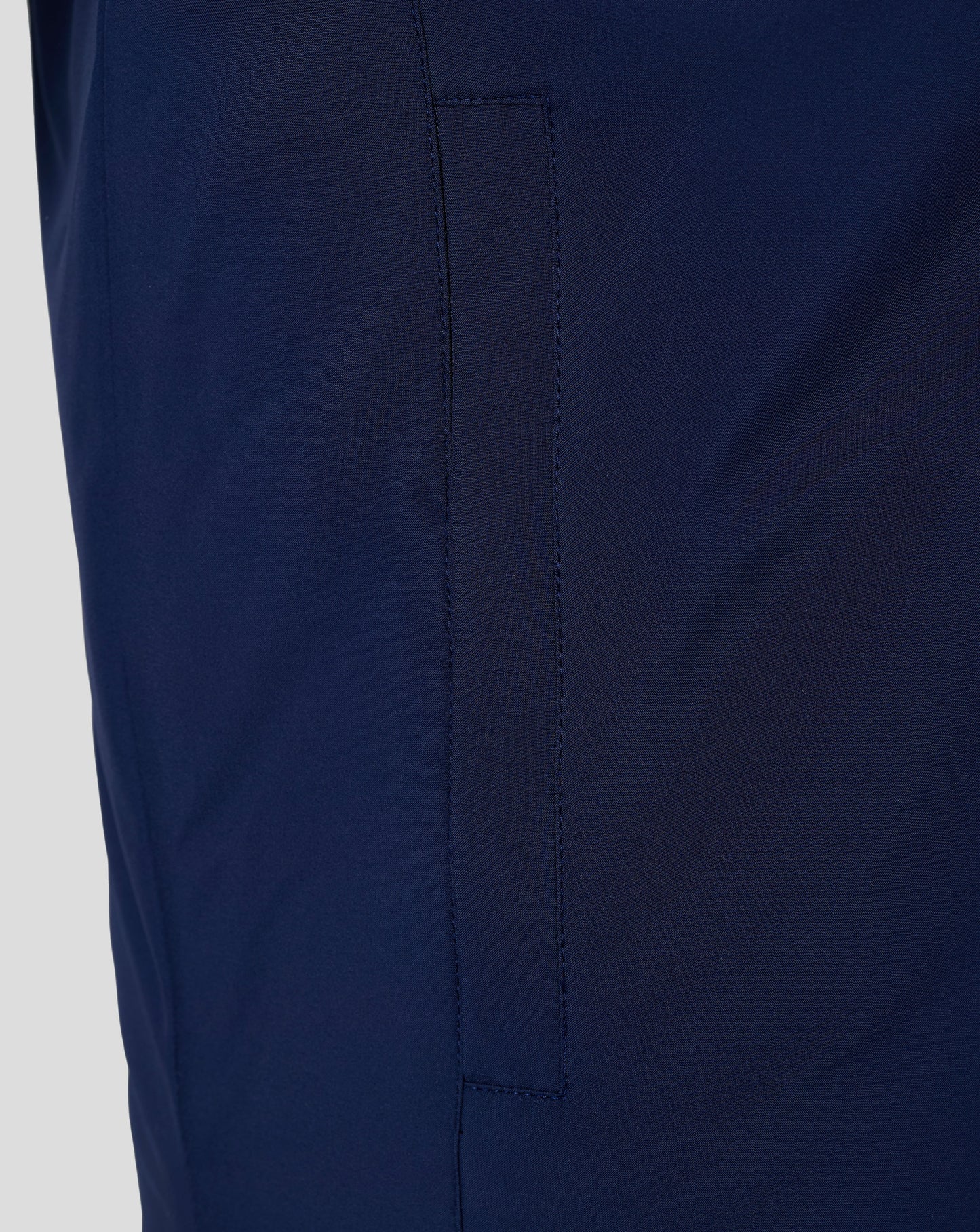 Close up of navy padded gilet fabric showing a vertical pocket seam and clean stitching.
