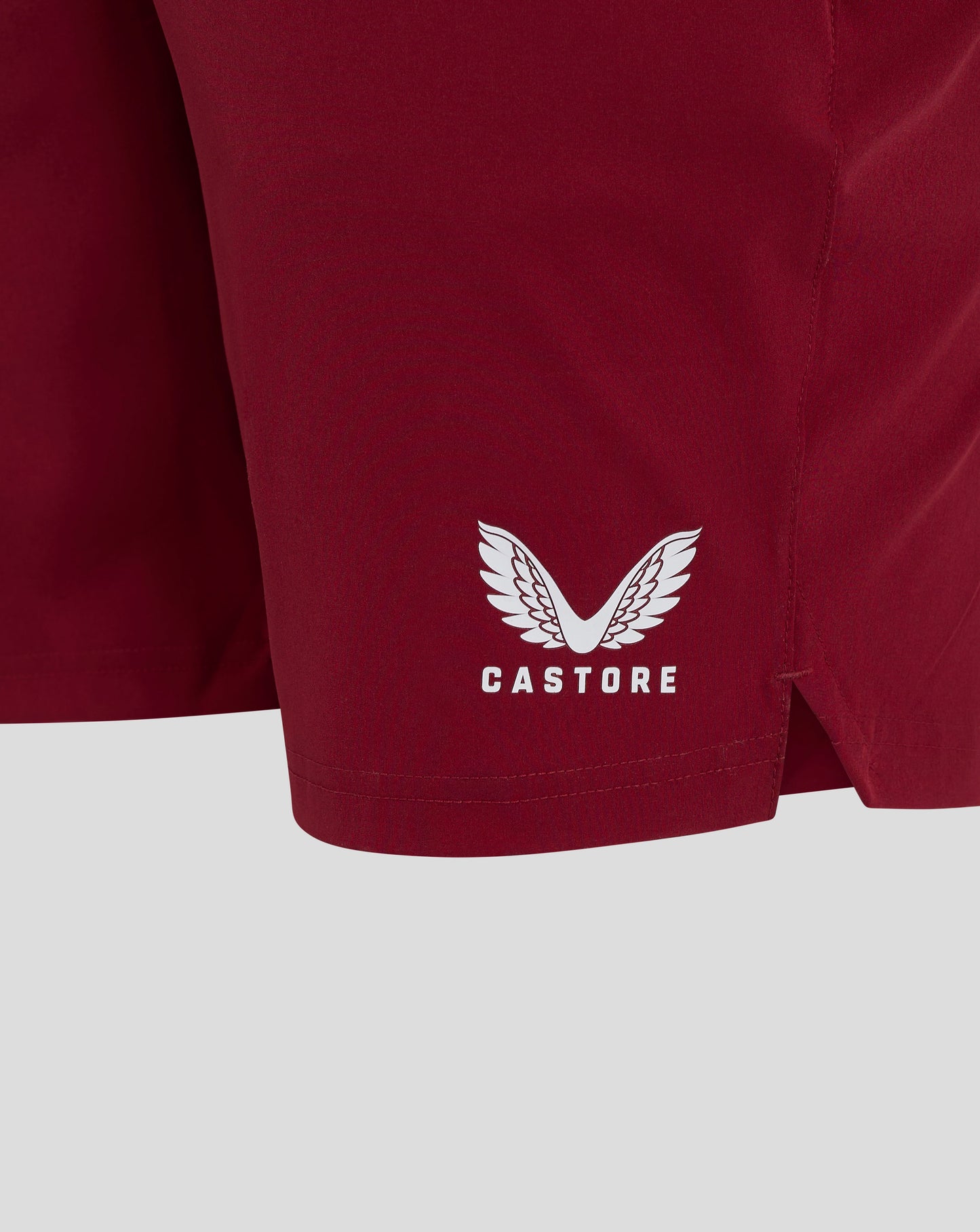 Close up of burgundy biking red shorts fabric with white Castore logo near the hem