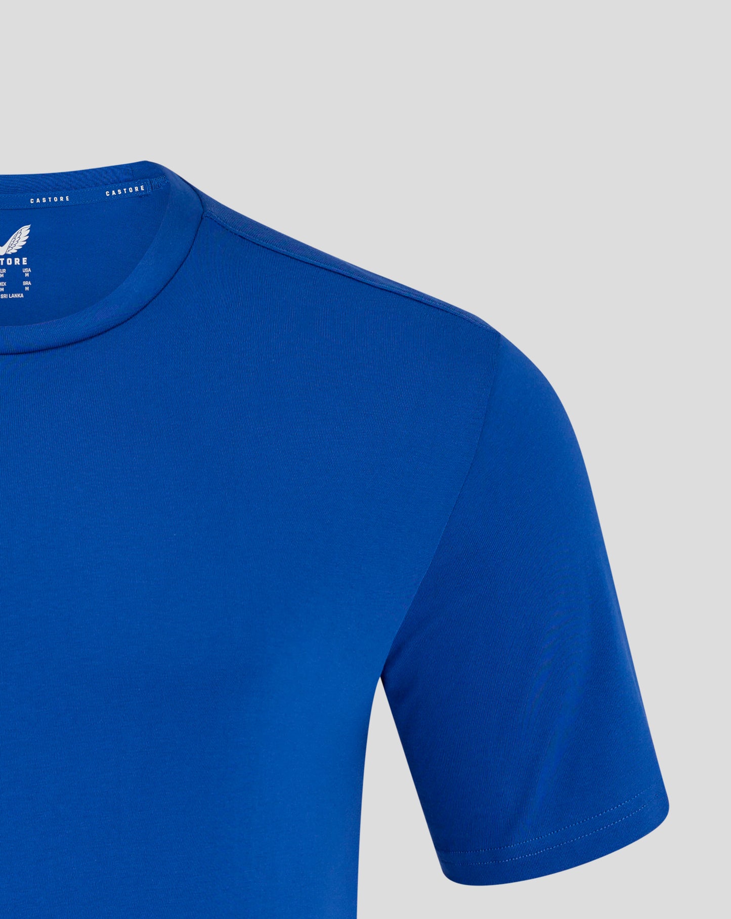 Shoulder and upper chest of blue Castore tee with visible white wing logo on the chest area