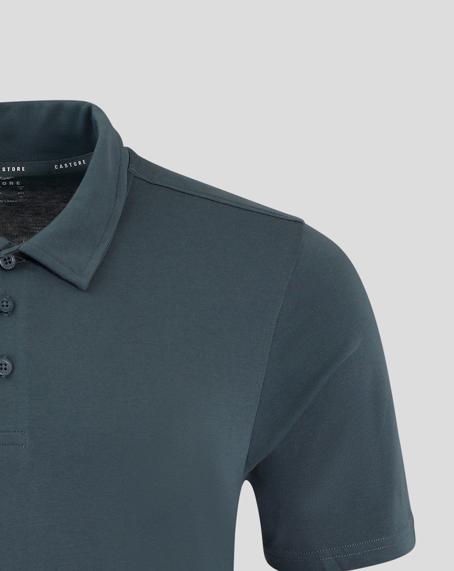 Shoulder and upper chest of dark slate polo with visible seam and Castore branding on interior label