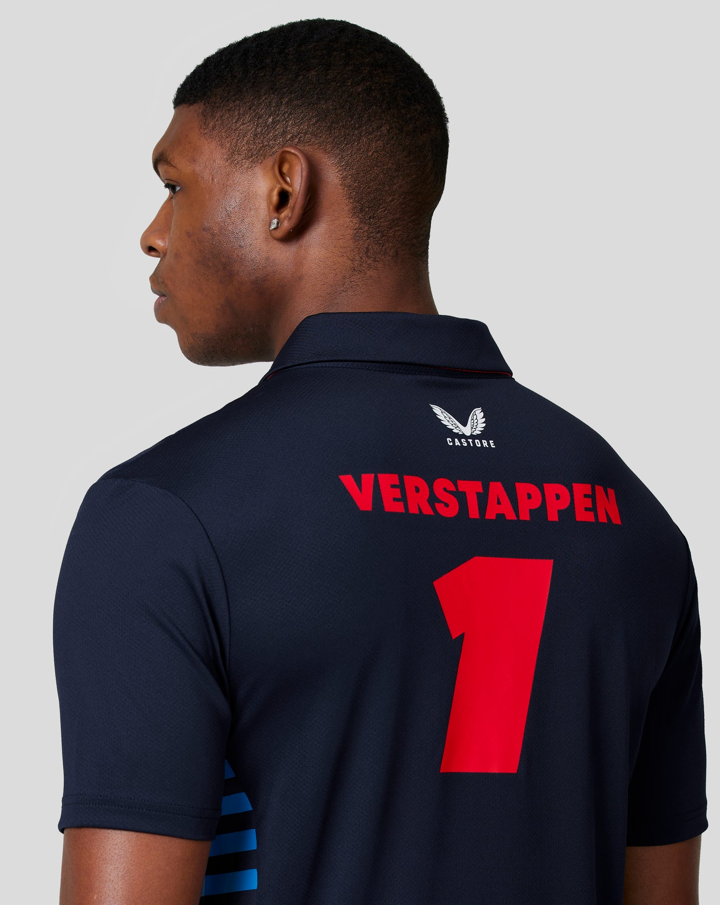 Side profile of male model in night sky Max Verstappen polo with team branding and Verstappen name on back