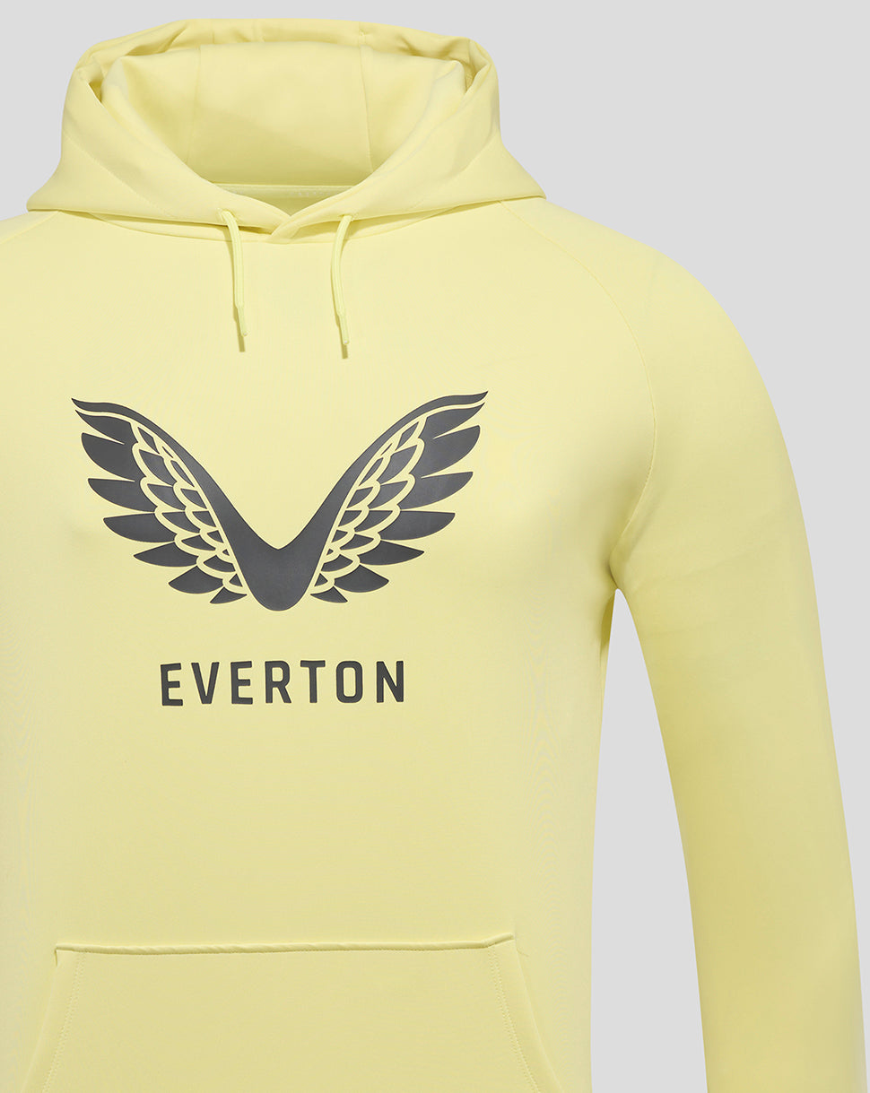 Pale yellow Everton training hoodie close up shows the wing logo and EVERTON lettering on the chest with hood visible.