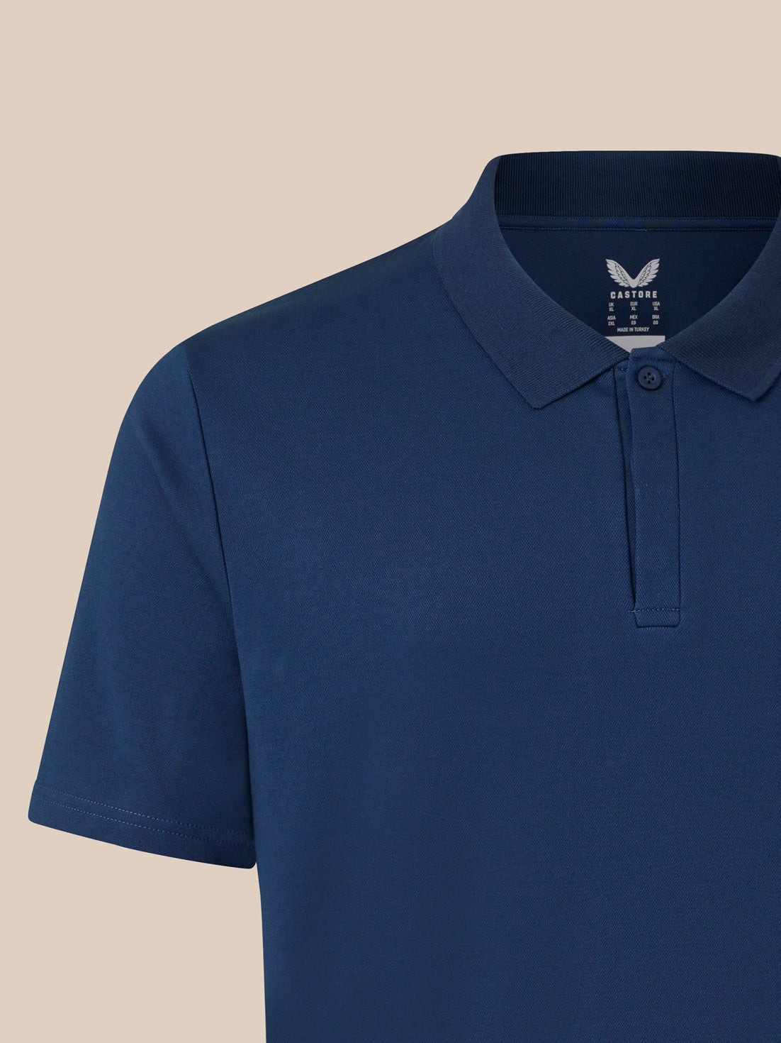 Detail of navy polo neck with embroidered Castore logo on the chest