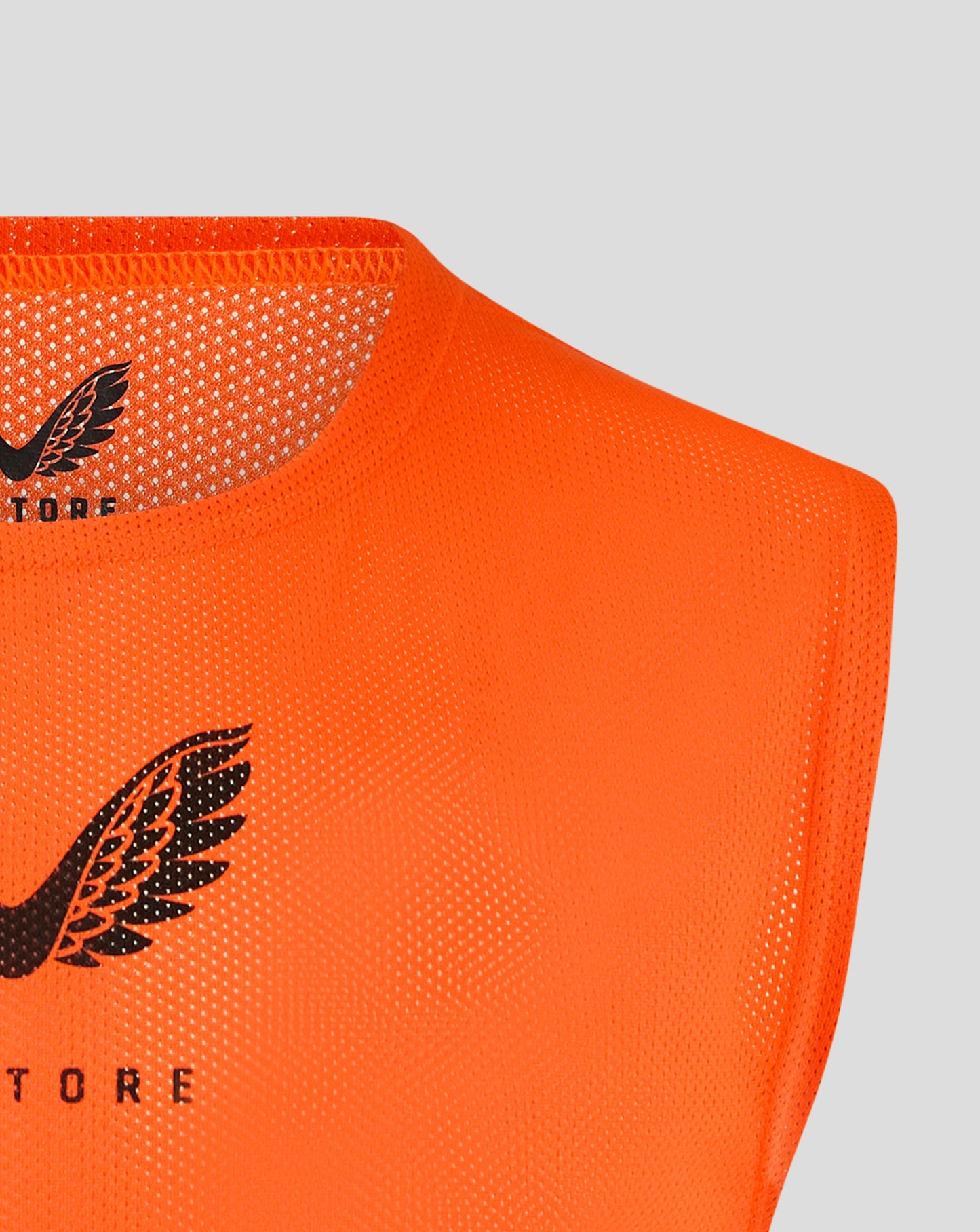 Neckline close up of orange training bib showing scoop neck and binding edge with Castore logo