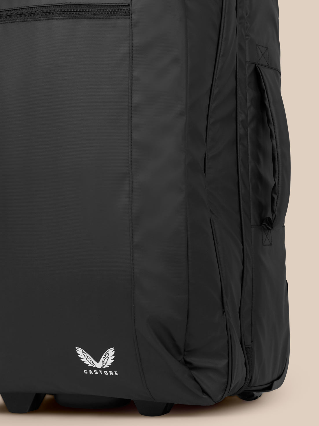 Close up of lower corner of black wheelie bag with wheel and Castore logo.
