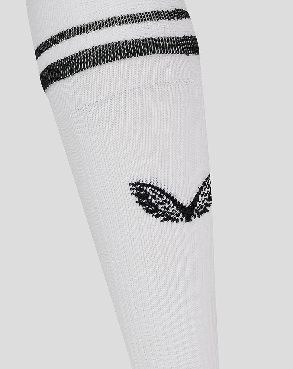 Close-up of white football sock showing black stripes at the cuff and a black emblem on the leg.