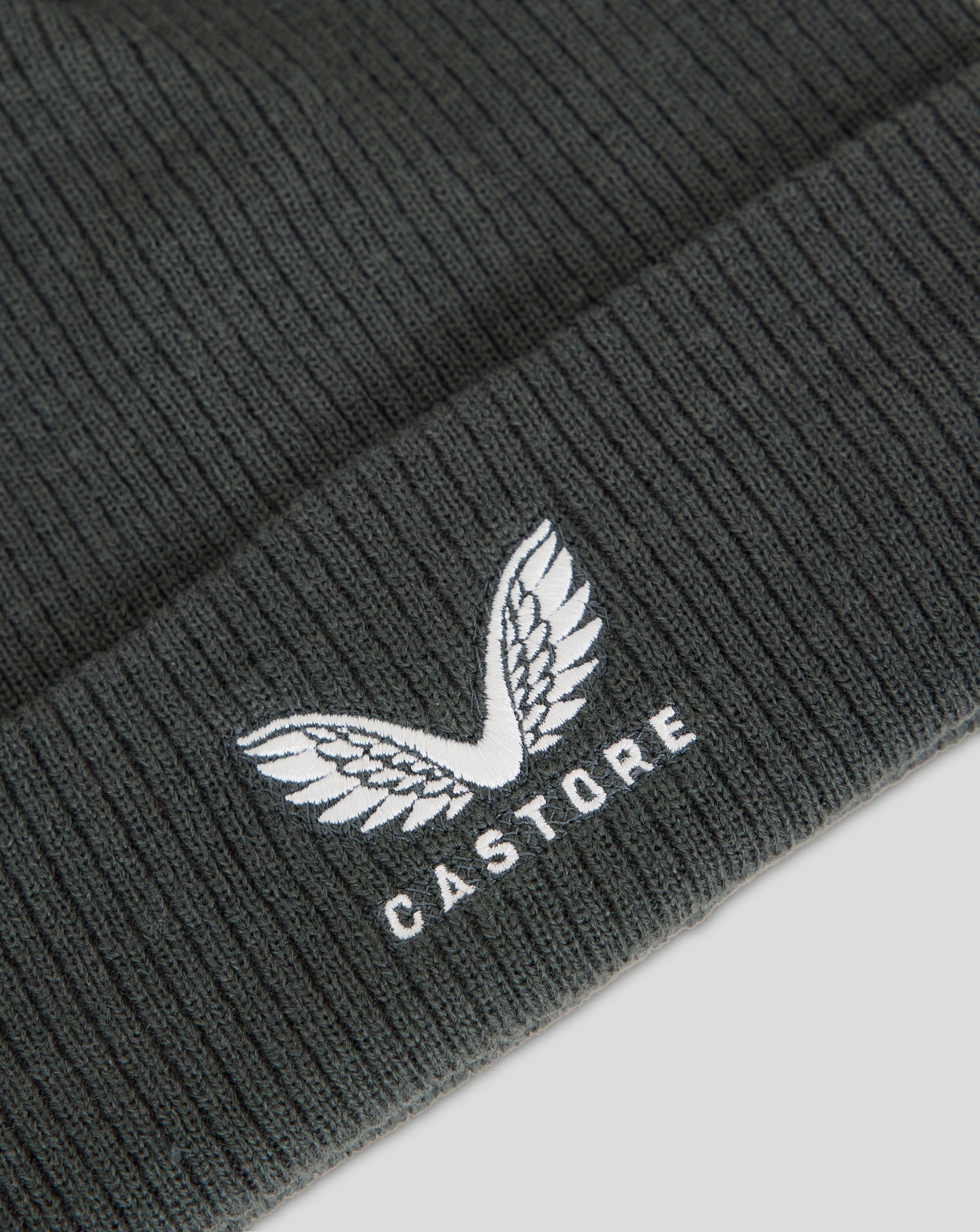 Dark slate ribbed knit beanie with fleece lining and embroidered Castore logo.
