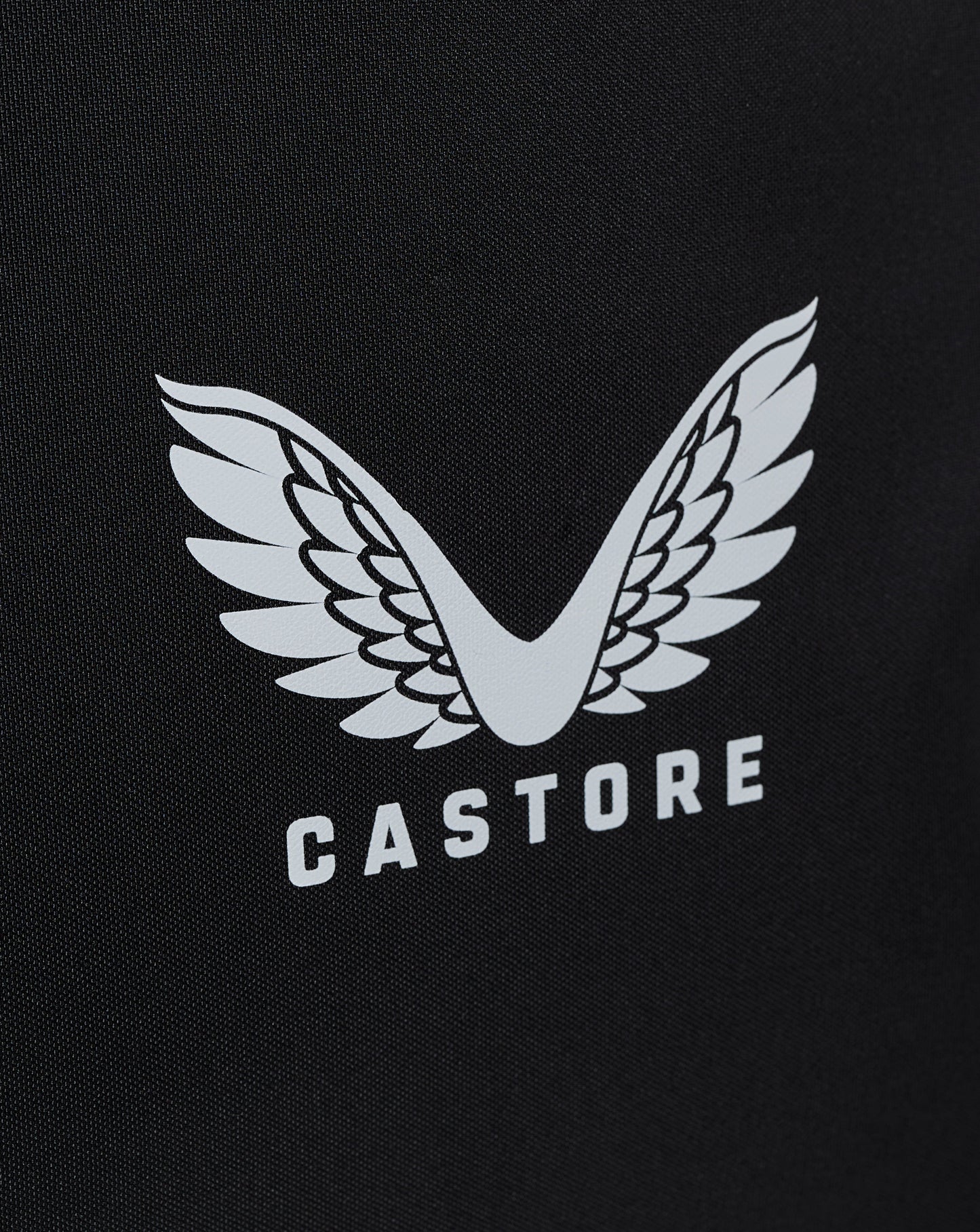 Close-up of white winged Castore logo on black bag fabric