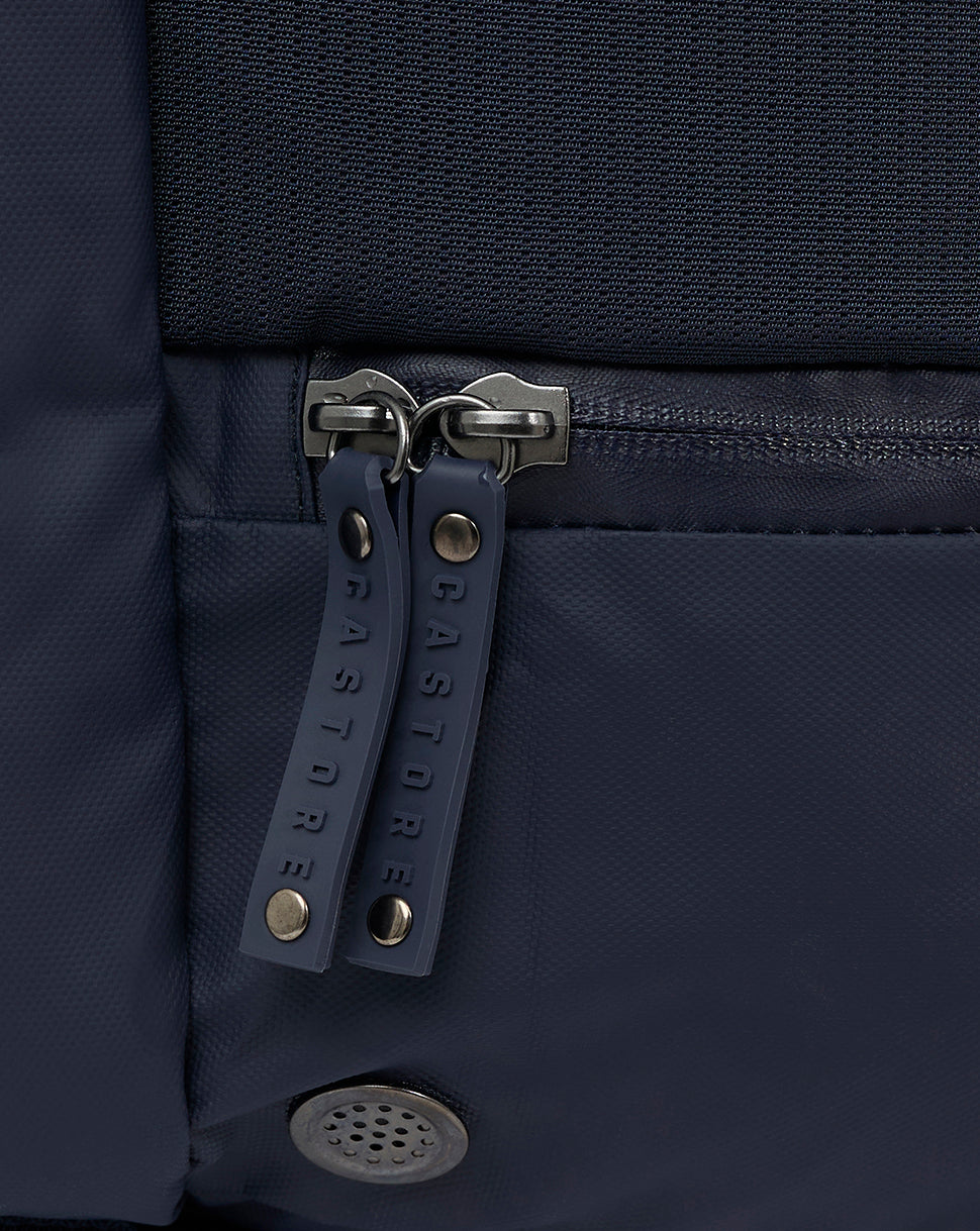 Close-up of twin navy zipper pulls on a backpack with metal hardware.