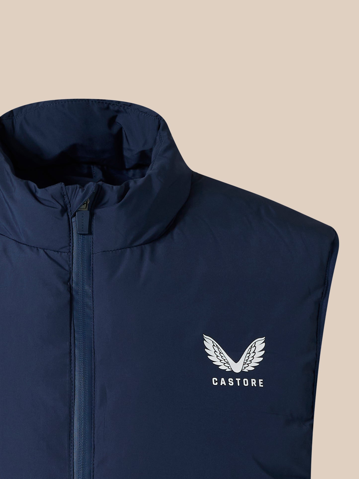 Navy padded unisex gilet with high collar and front zipper, Castore logo visible on the lower front.