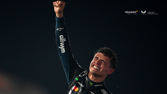 Clenched fist raised in celebration by a racing driver in a McLaren racing suit.