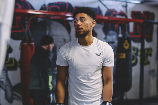 Castore boxer Niall Brown stands in a gym wearing a white shirt