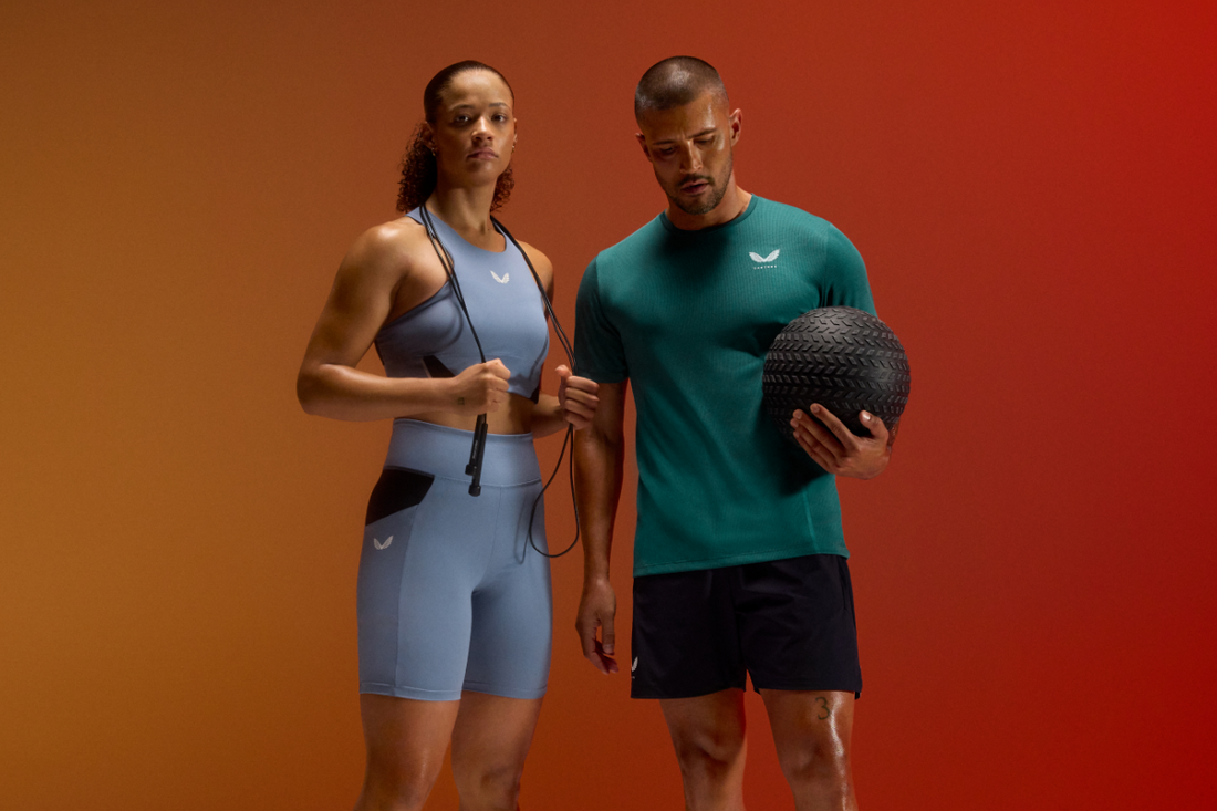 Athletes in Apex HIIT outfits pose in a studio, woman in blue matching set and man in teal top with a textured exercise ball.