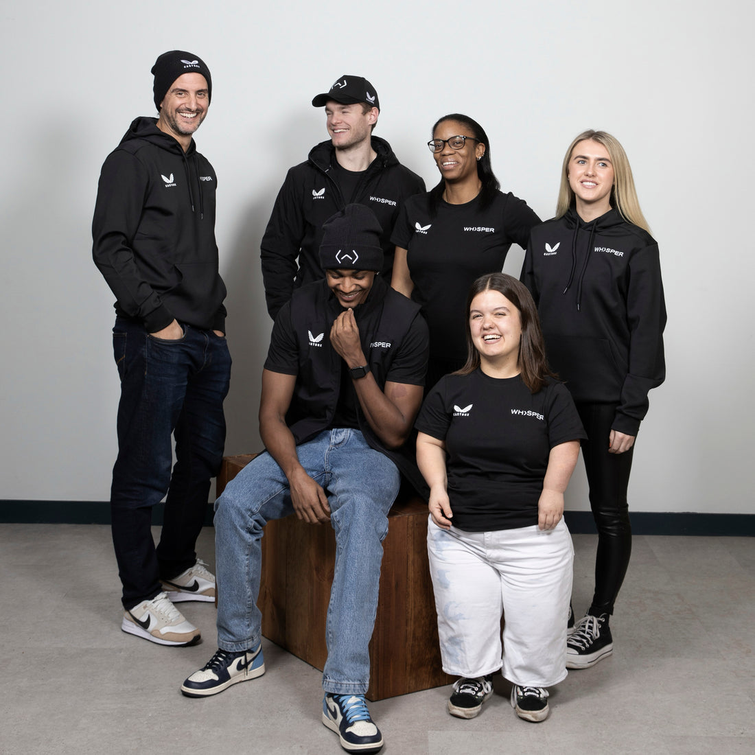 Group of models wearing black Castore x Whisper TV Kit apparel posing together.