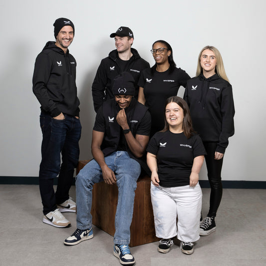 Group of models wearing black Castore x Whisper TV Kit apparel posing together.