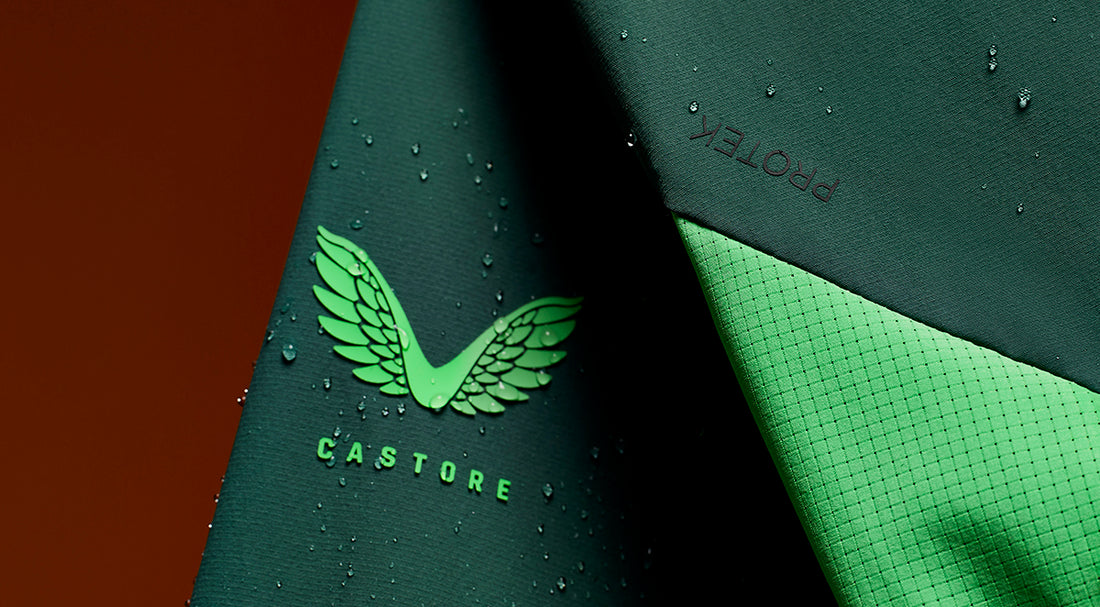 Close up of Castore fabric with a green wing logo and a textured surface with droplets.