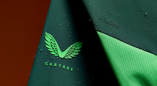 Close up of Castore fabric with a green wing logo and a textured surface with droplets.