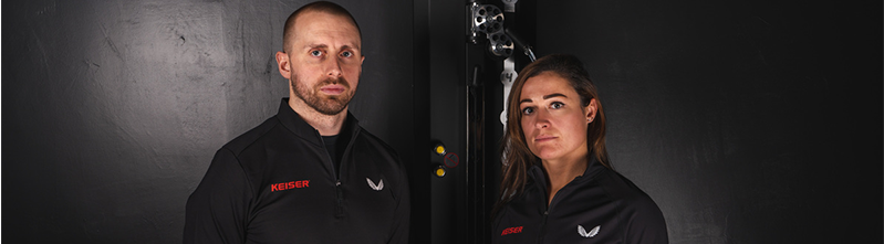 Castore x Keiser partnership launch photo with two people in branded black gear