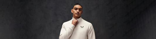 Male model in a cream turtleneck against a dark studio backdrop promoting the scuba collection