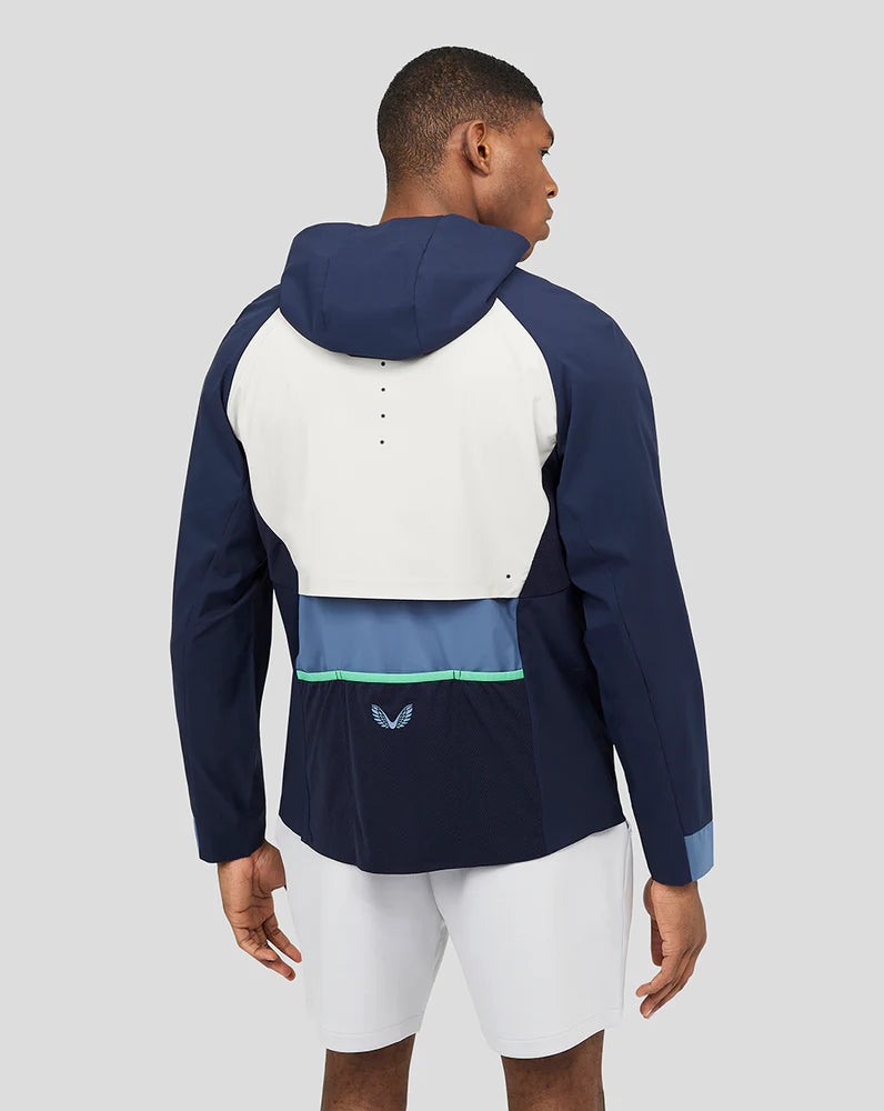 Back view of a model in a navy and white hooded Proteus jacket with color block panels.