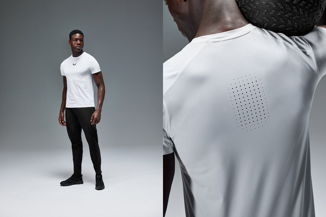 Male model wearing a white Zone Collection lightweight training shirt stands against a gray backdrop with a close up of the perforated back panel.