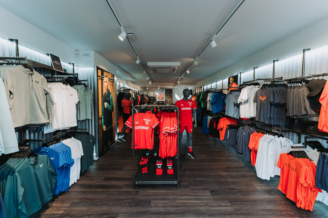 Castore store interior filled with athletic apparel on racks and mannequins under bright lighting.