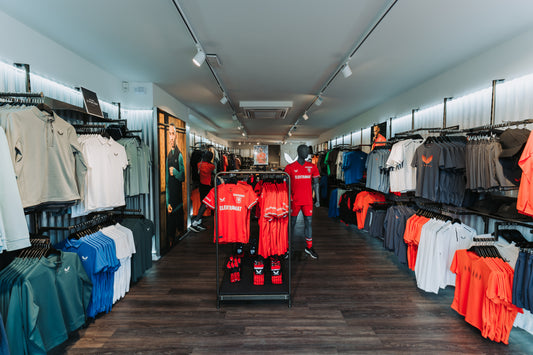 Castore store interior filled with athletic apparel on racks and mannequins under bright lighting.