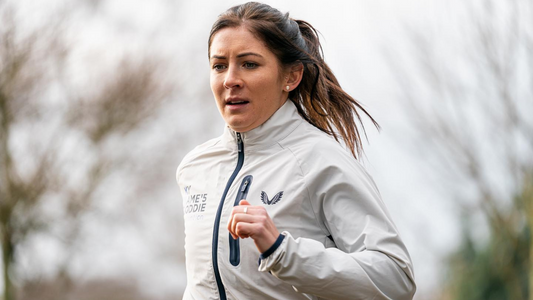 Woman running outdoors in a light jacket during training