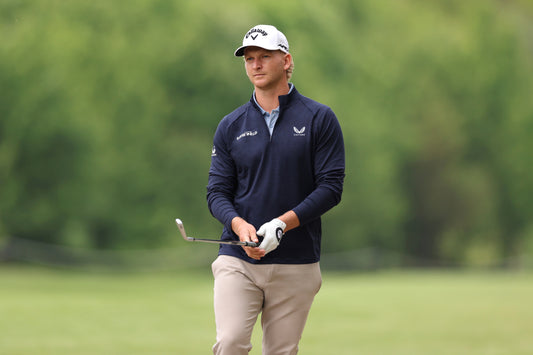 German professional golfer wearing a navy Castore polo and holding a golf club on a green course
