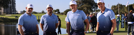 Four men in light blue polo shirts and white caps stand together on a golf course during a Majesticks GC partnership event.