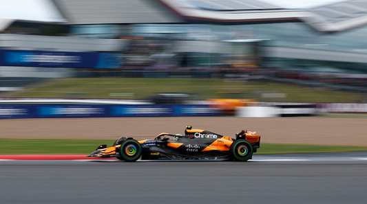 Orange and black Formula 1 car speeds along a race track with a blurred background