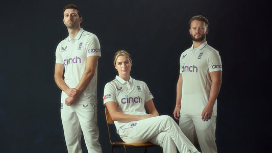 Three England cricket players pose in white test kits with cinch sponsor logos against a dark studio backdrop.