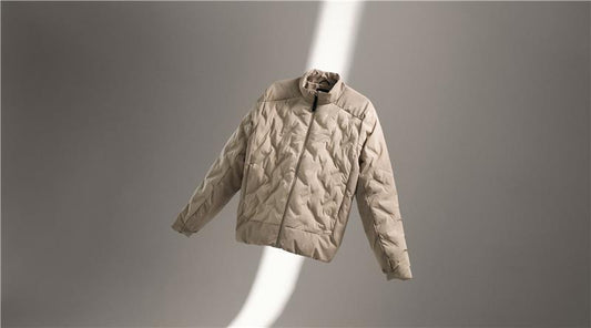 Beige quilted jacket floating against a soft gray backdrop showcasing winter layering