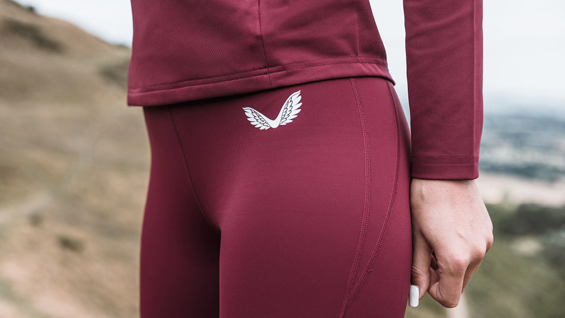 Close up of burgundy leggings with a white wing logo on the back waistband
