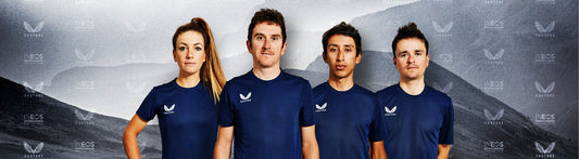 Group of four Castore athletes in navy shirts posing against a gray backdrop with INEOS Grenadiers branding