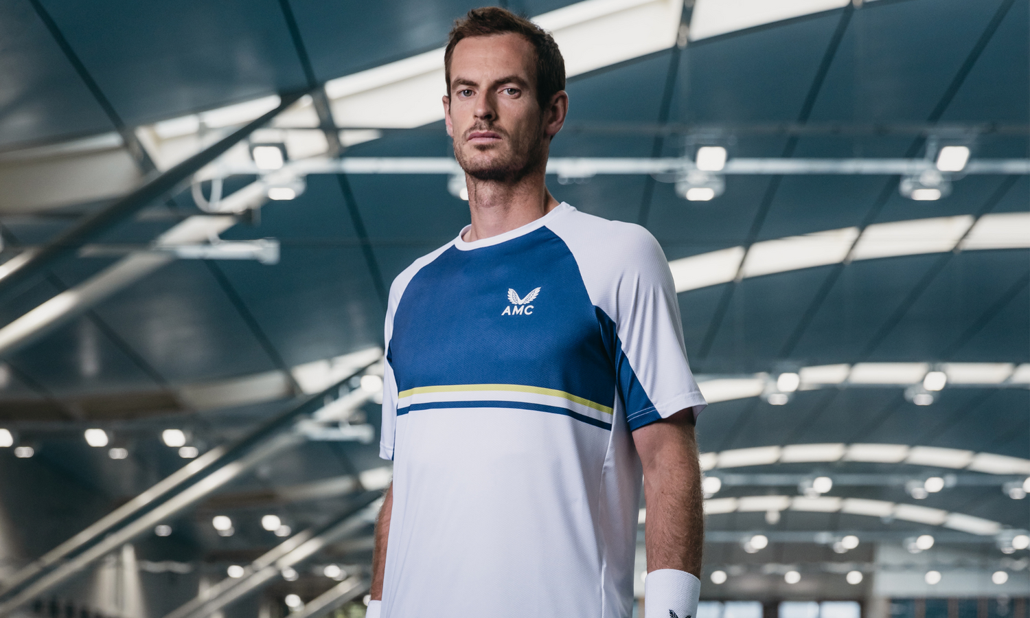 Male model wearing a blue white color block AMC athletic tee in a modern showroom setting