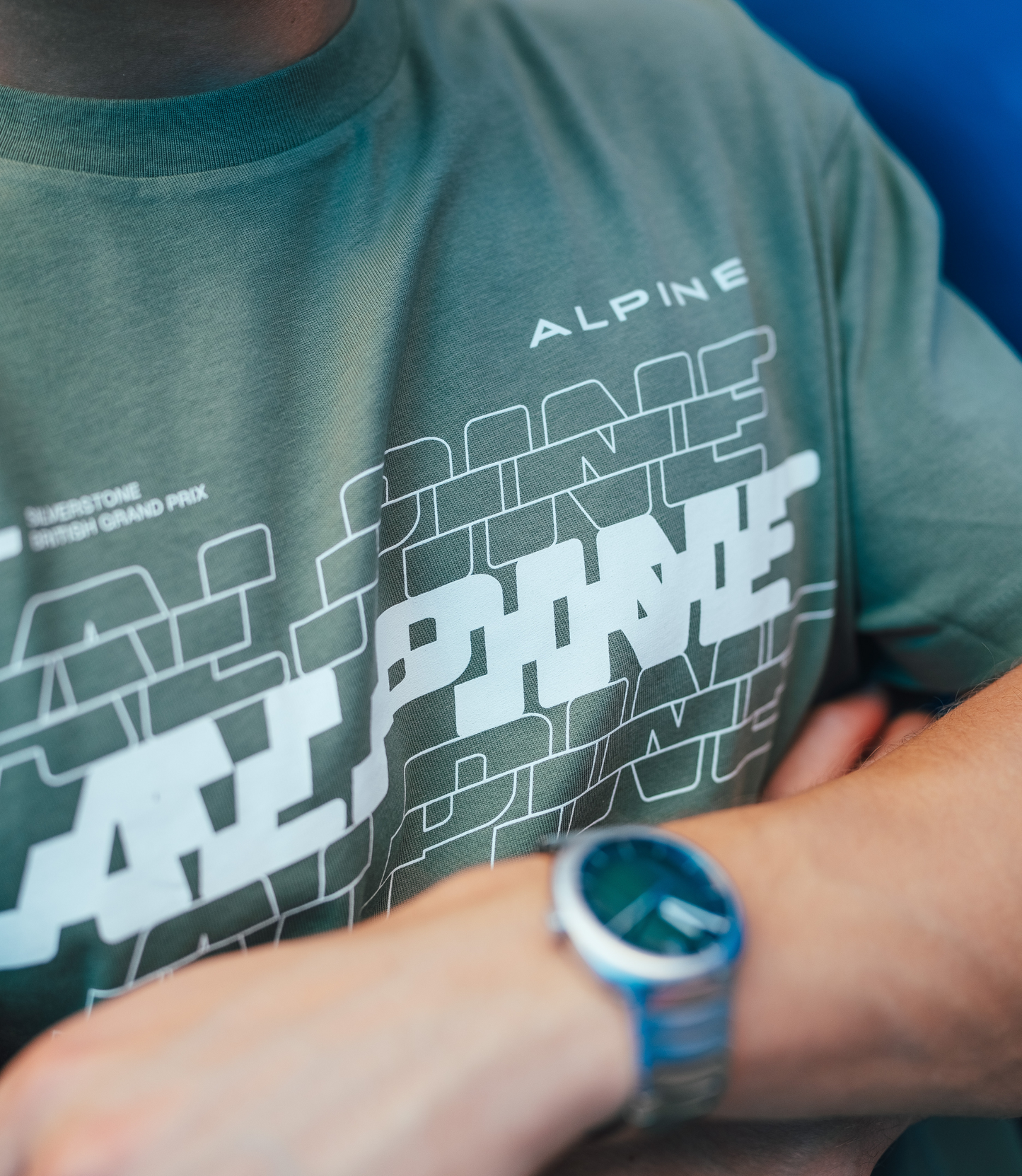 Close up of green Alpine T shirt chest showing Alpine branding and layered graphic design