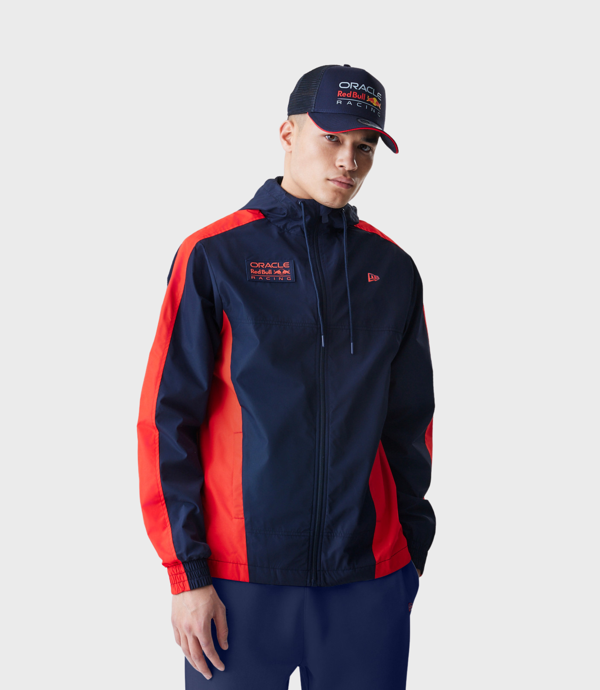 Man wearing navy Oracle Red Bull Racing Windrunner jacket with red panels and embroidered logos.