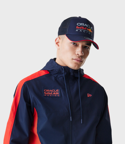 Man wearing dark blue Red Bull Racing Windrunner jacket with Oracle patch on chest and Oracle Red Bull Racing cap.