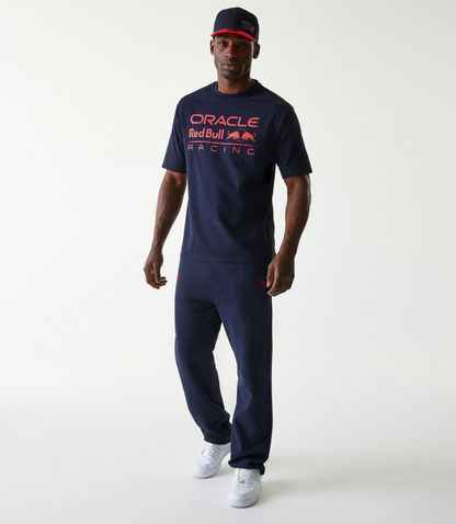 Front view of a man wearing a navy cap with red brim and a dark blue oversized Oracle Red Bull Racing T shirt